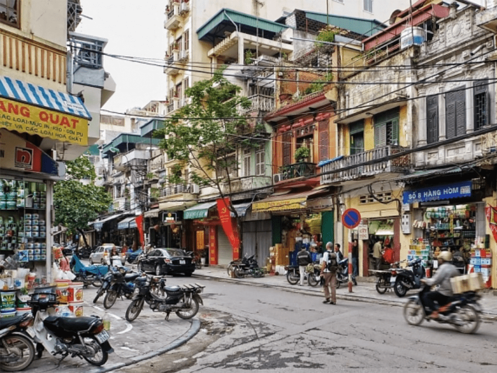 View of the bustling Old Quarter streets in Hanoi, with colorful shops and scooters.