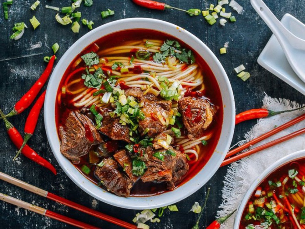 A vibrant street-side restaurant in Hanoi serving traditional phở bò sốt vang.