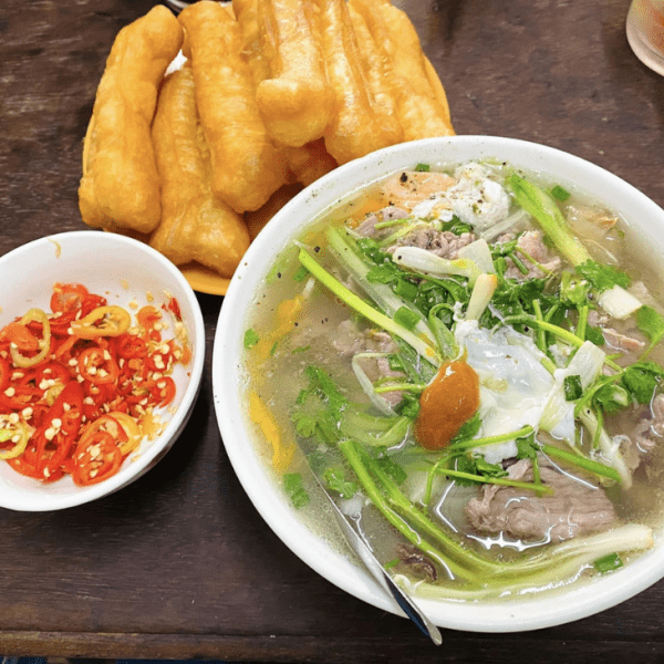 A clear, delicate bowl of Hanoi pho with fresh herbs and beef slices.