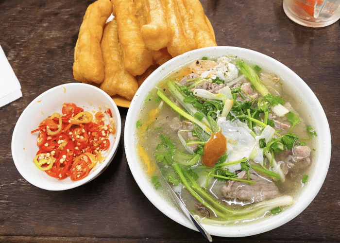 A clear, delicate bowl of Hanoi pho with fresh herbs and beef slices.