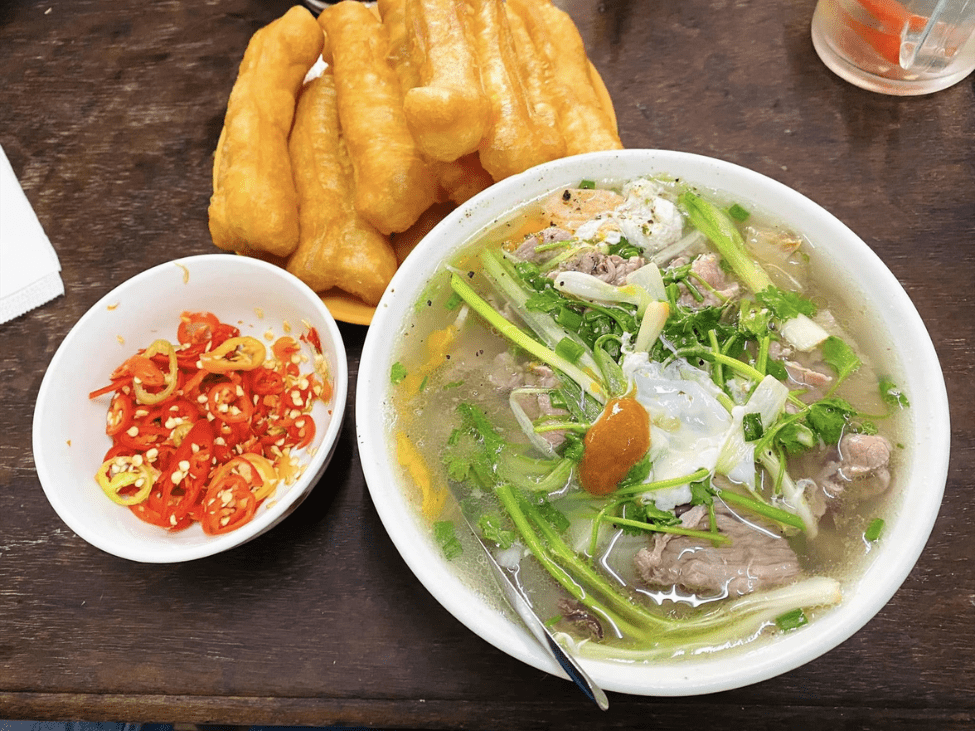 A clear, delicate bowl of Hanoi pho with fresh herbs and beef slices.