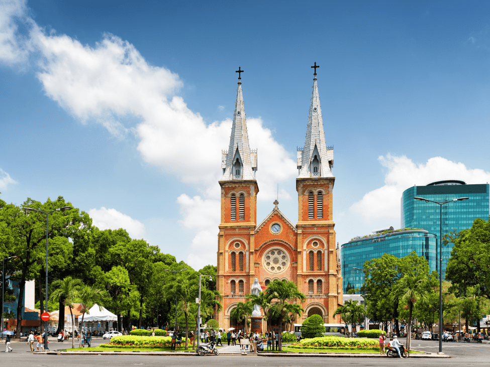 Busy street scene in Ho Chi Minh City with motorbikes and the iconic Notre Dame Cathedral in the background.