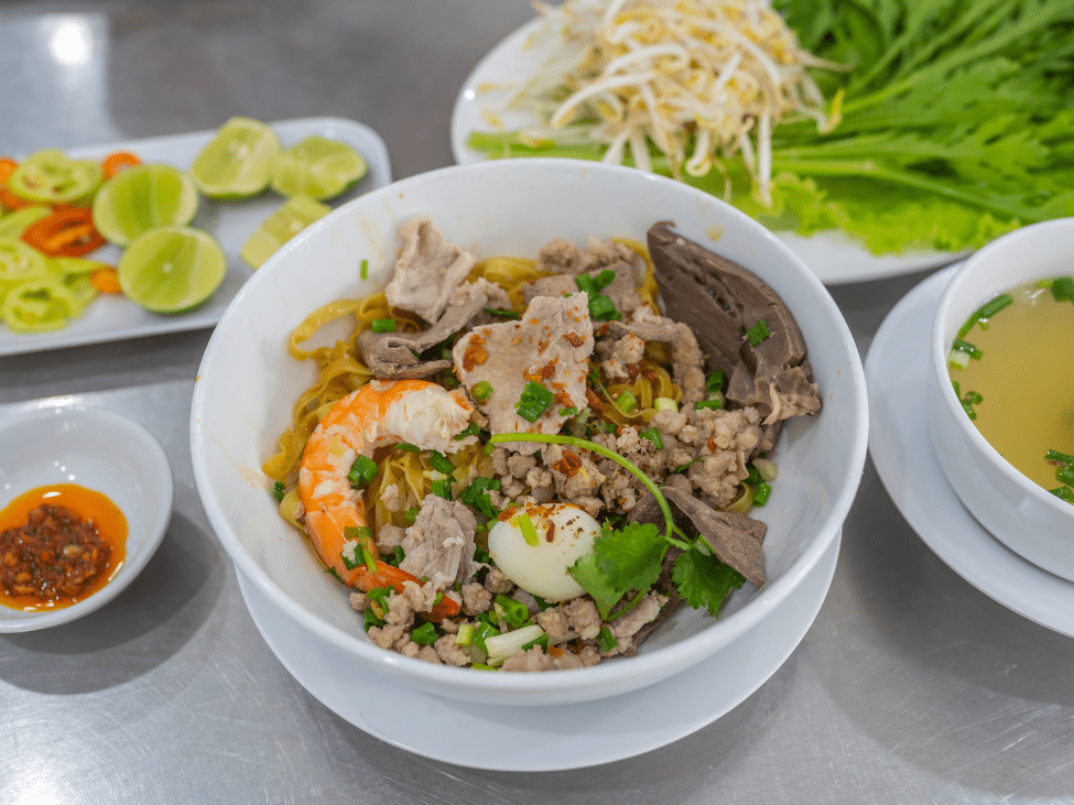 A bowl of Hu Tieu with a mix of seafood and pork in a clear broth.