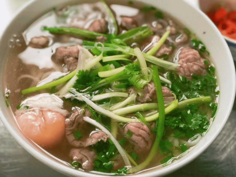 A pot of homemade pho broth simmering with beef bones, spices, and vegetables.