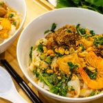 A bowl of Mi Quang with shrimp, pork, herbs, and rice cracke