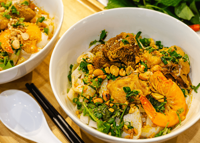 A bowl of Mi Quang with shrimp, pork, herbs, and rice cracke