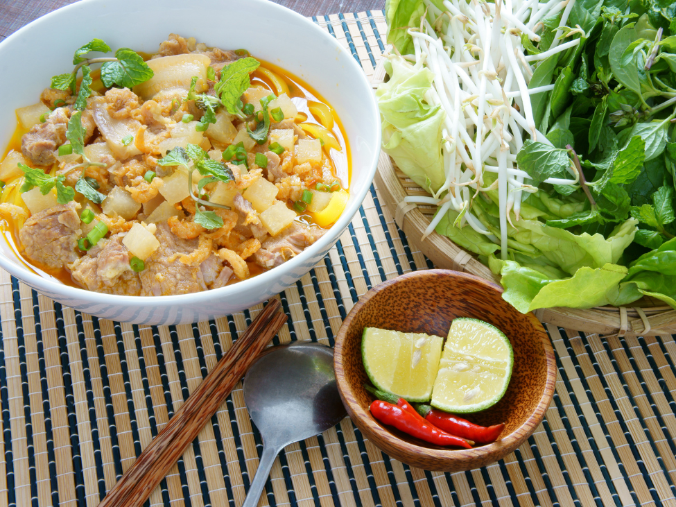 A vibrant bowl of Mi Quang with yellow noodles, pork, and shrimp.