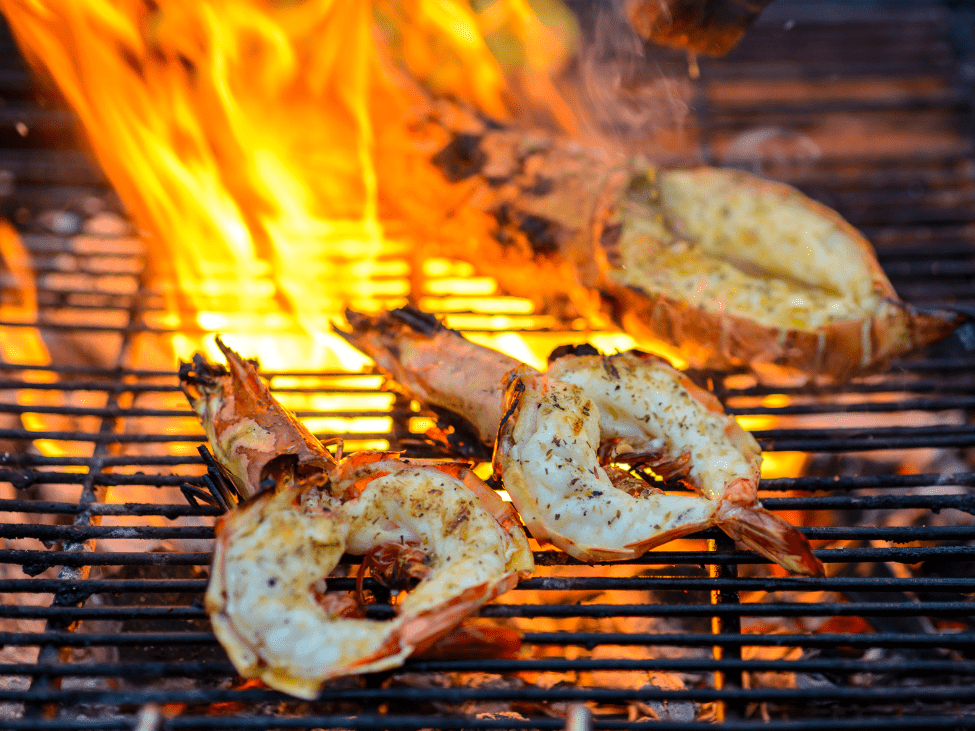 A plate of grilled prawns with scallion oil at Ốc Đào, served with fresh herbs and stir-fried snails.