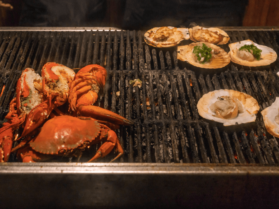 A plate of prawns and clams grilled with garlic butter at Ốc Linh, served with steamed snails on the side.