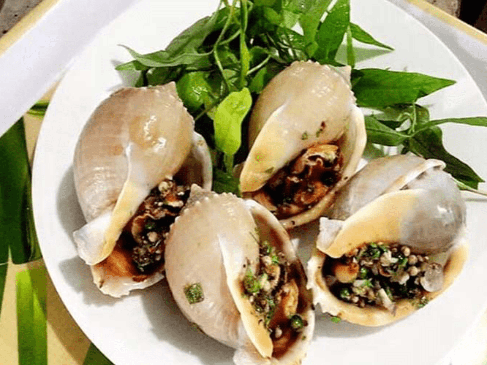 A plate of grilled snails with butter and garlic at Ốc Như, alongside coconut milk prawns.