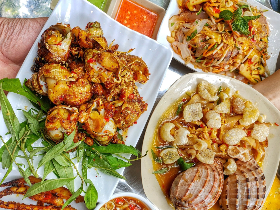 A spread of different snail dishes served alongside grilled seafood at Ốc Thảo.