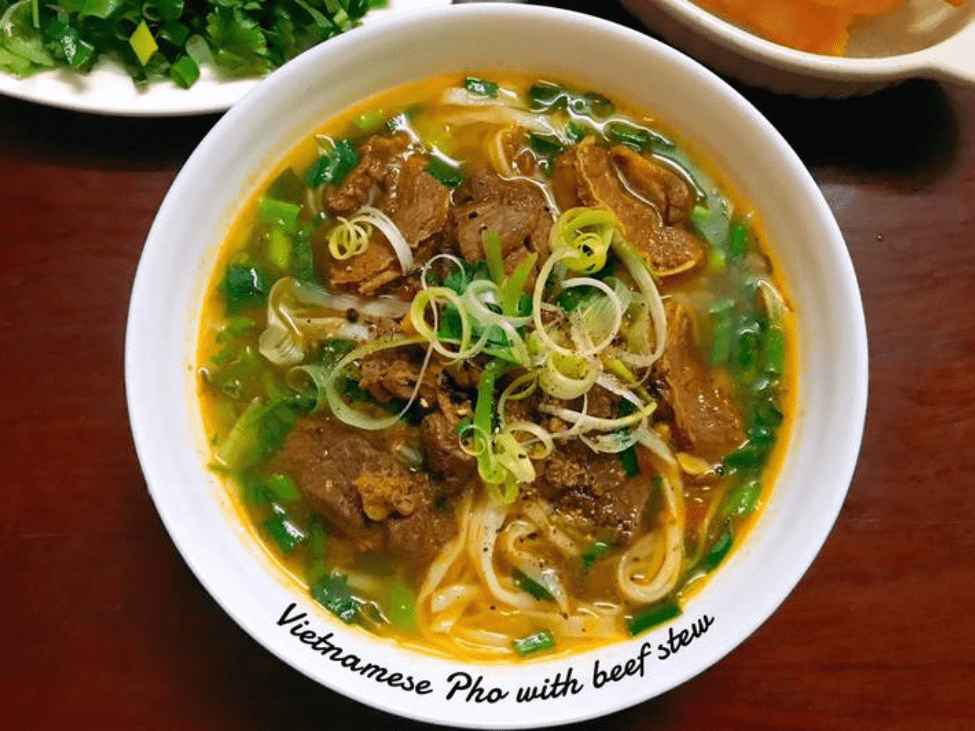 A steaming bowl of phở bò sốt vang served with fresh herbs in Hanoi.