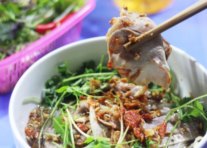 A colorful bowl of sour noodles from Lạng Sơn, featuring rice noodles, shredded chicken, and fresh herbs.