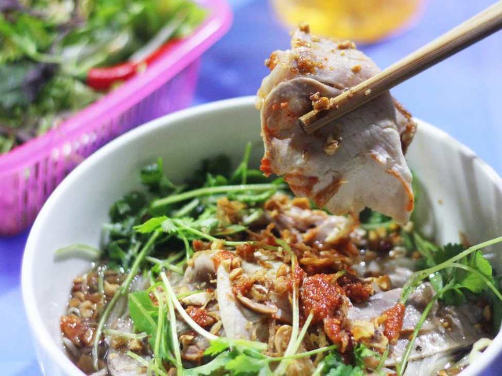 A colorful bowl of sour noodles from Lạng Sơn, featuring rice noodles, shredded chicken, and fresh herbs.