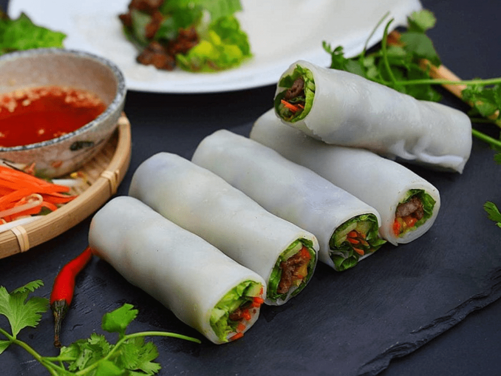 Pho cuốn rolls filled with beef and fresh herbs on a plate.