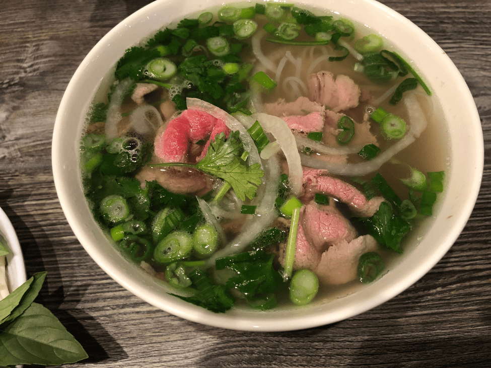 A steaming bowl of pho Ha noi with rich beef broth, rice noodles, and fresh herbs. 