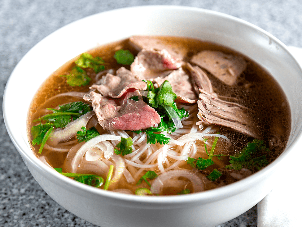 A steaming bowl of traditional pho Hanoi with clear broth and tender beef slices.