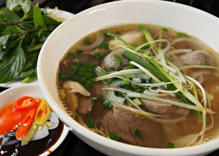 Pho Le's iconic bowl of pho with meatballs and a side of bean sprouts.