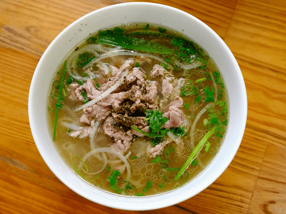 A bowl of Phở Sướng with thick rice noodles and fresh herbs.