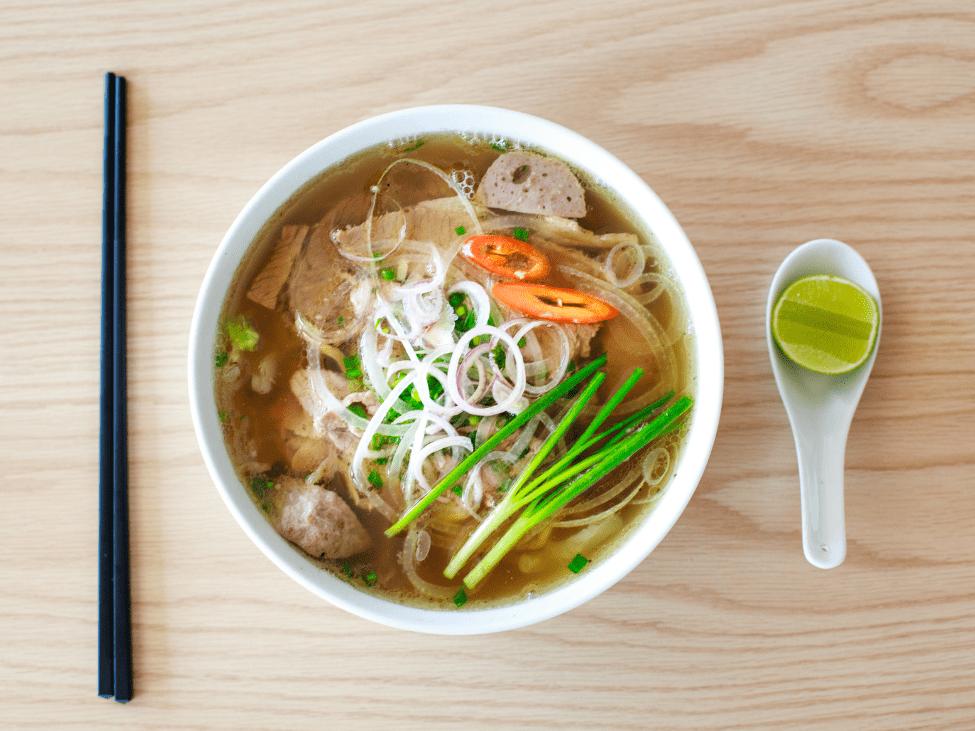 A vibrant bowl of Phở Sướng with a side of fresh herbs and lime wedges, ready to be enjoyed.