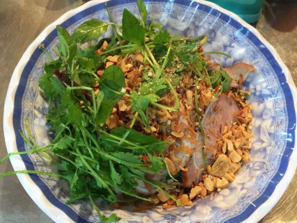 Phở tíu with barbecued pork and fresh herbs on a plate.