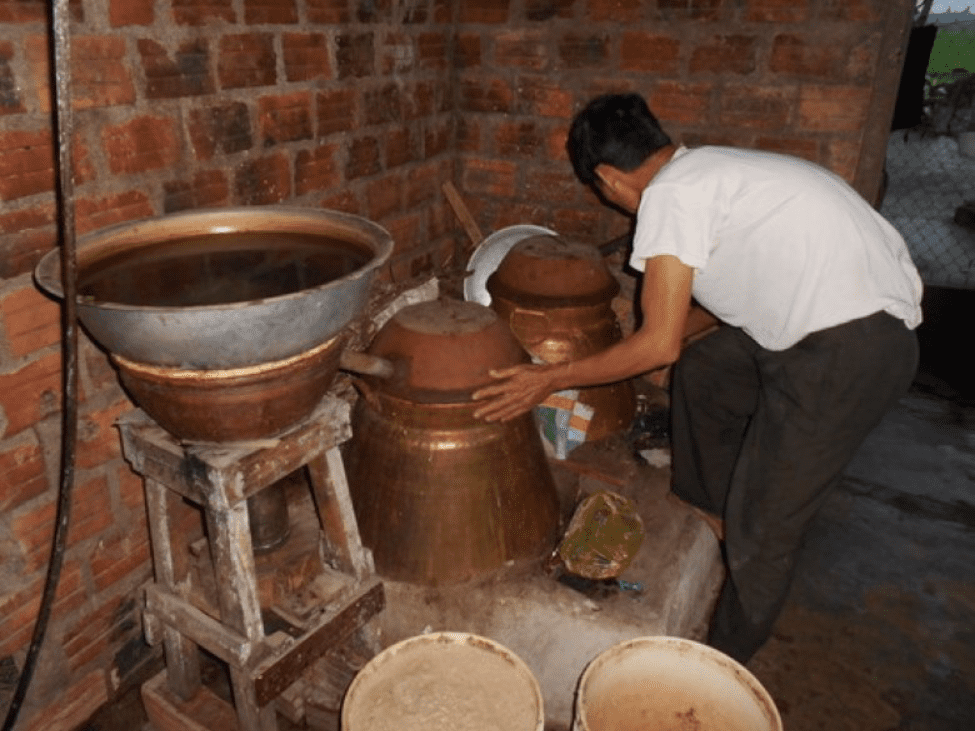 Large earthen jars used for fermenting and distilling traditional rice wine in a village workshop.