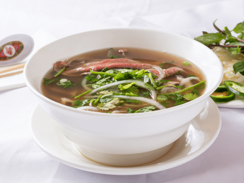 A street vendor in Saigon preparing a bowl of pho for early morning customers.