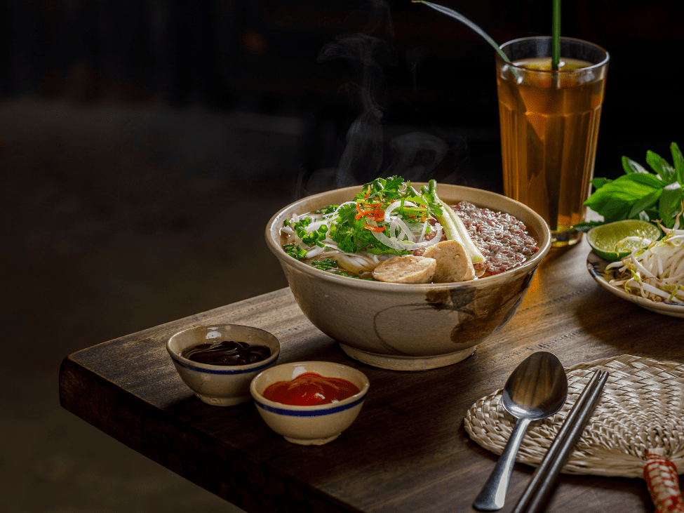 Traditional pho toppings like bean sprouts, Thai basil, and lime wedges on a plate.