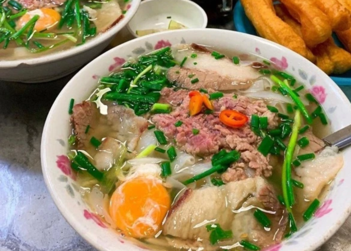 A bowl of pho with unique toppings like quail eggs, fried shallots, and pickled garlic.