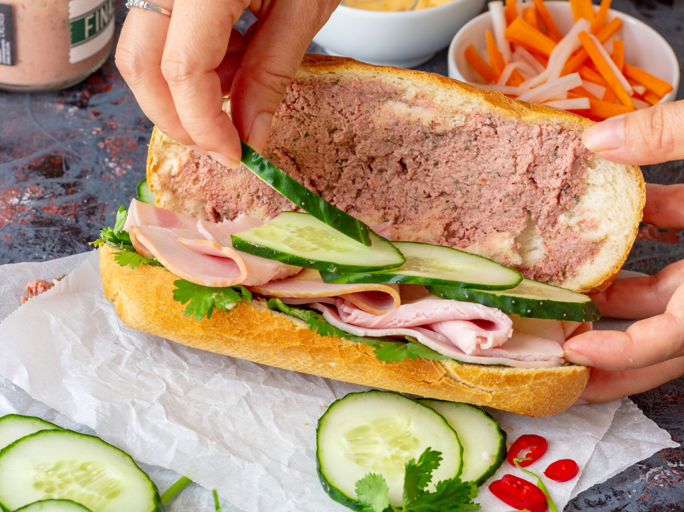 Close-up of a traditional Vietnamese Bánh Mì sandwich with fresh herbs and pork.