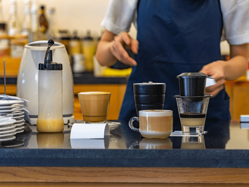 A busy Vietnamese coffee shop with people enjoying various types of coffee.