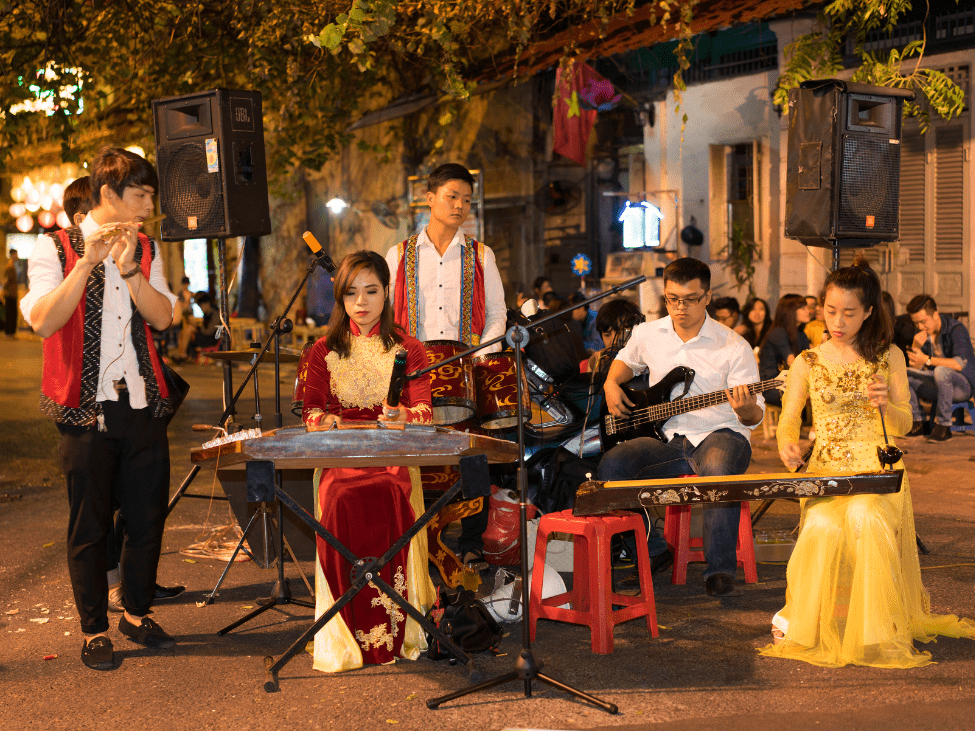 Musicians perform a traditional Vietnamese folk song using ancient instruments at a rural festival.