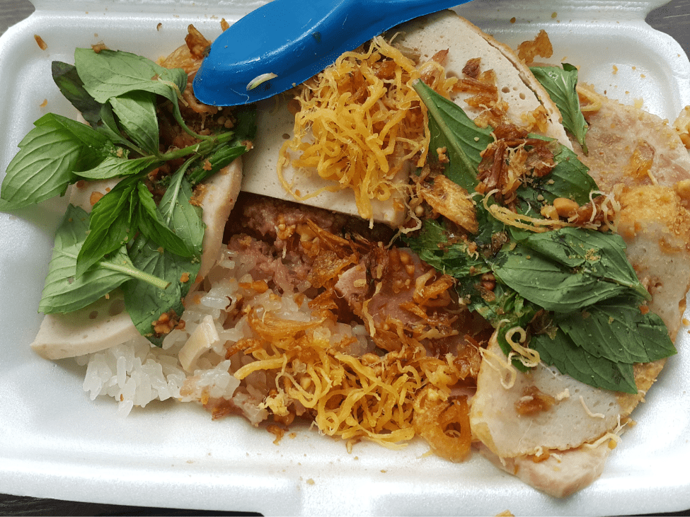 A plate of xôi sticky rice topped with shredded chicken and mung beans.