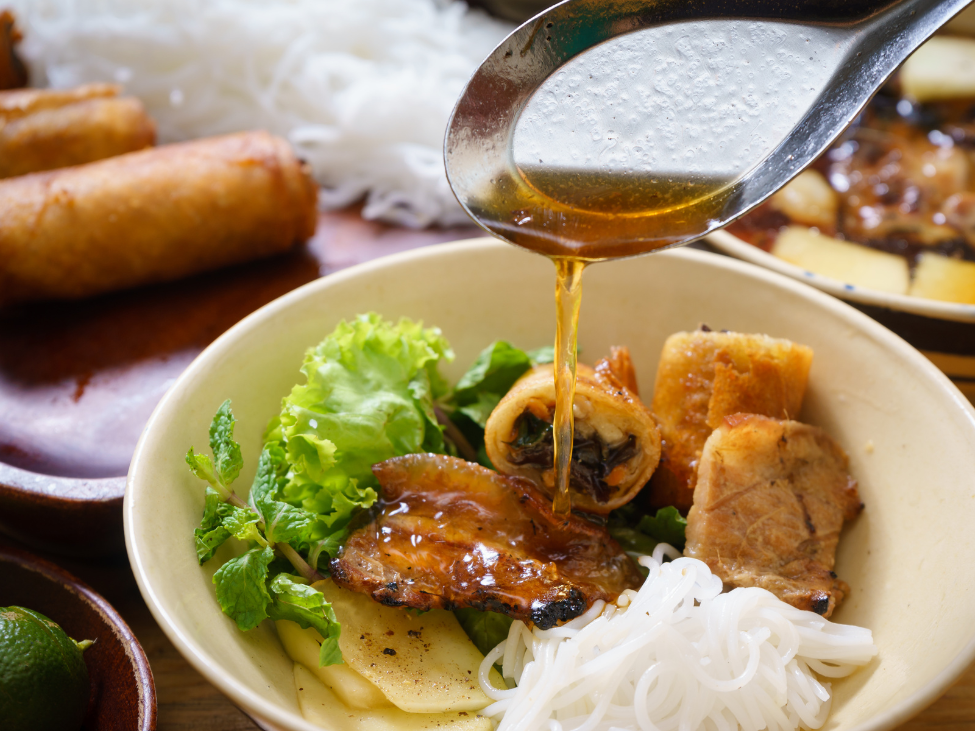 Bowl of Bun Cha with herbs and sauce in Hanoi Old Quarter