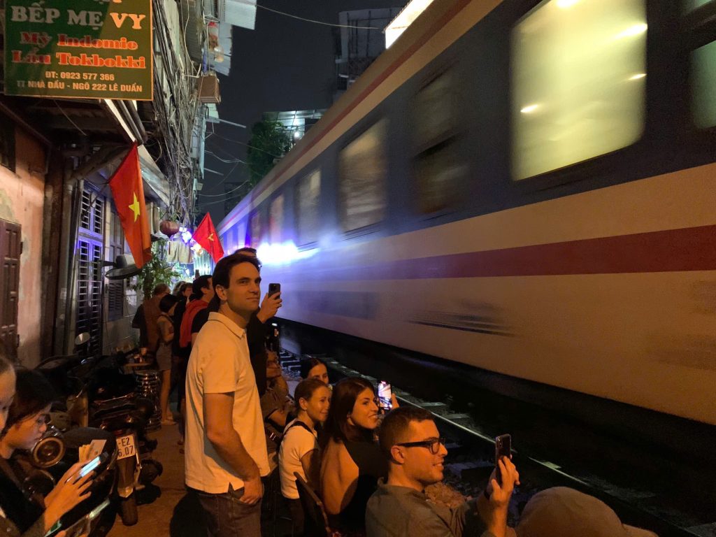 Close-up of a camera capturing a train passing through Hanoi Train Street.