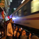 Close-up of a camera capturing a train passing through Hanoi Train Street.