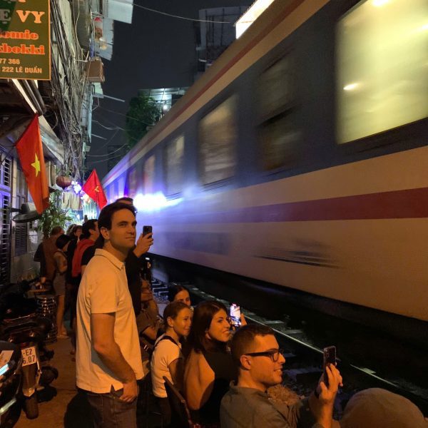 Close-up of a camera capturing a train passing through Hanoi Train Street.