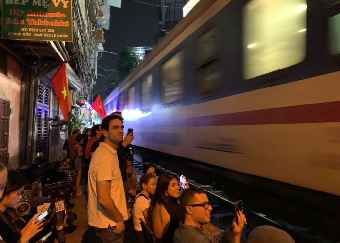 Close-up of a camera capturing a train passing through Hanoi Train Street.