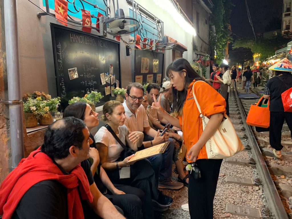 Visitors enjoying a safe coffee experience near the train tracks in Hanoi.