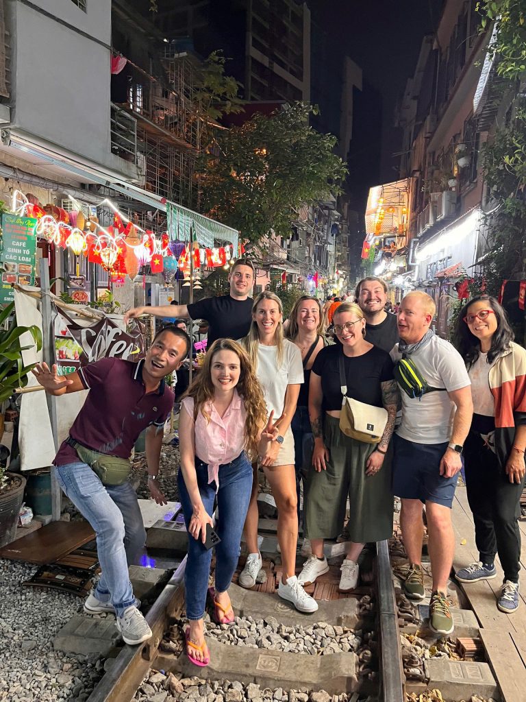 Tourists enjoying a vibrant moment on Hanoi Train Street with a passing train.