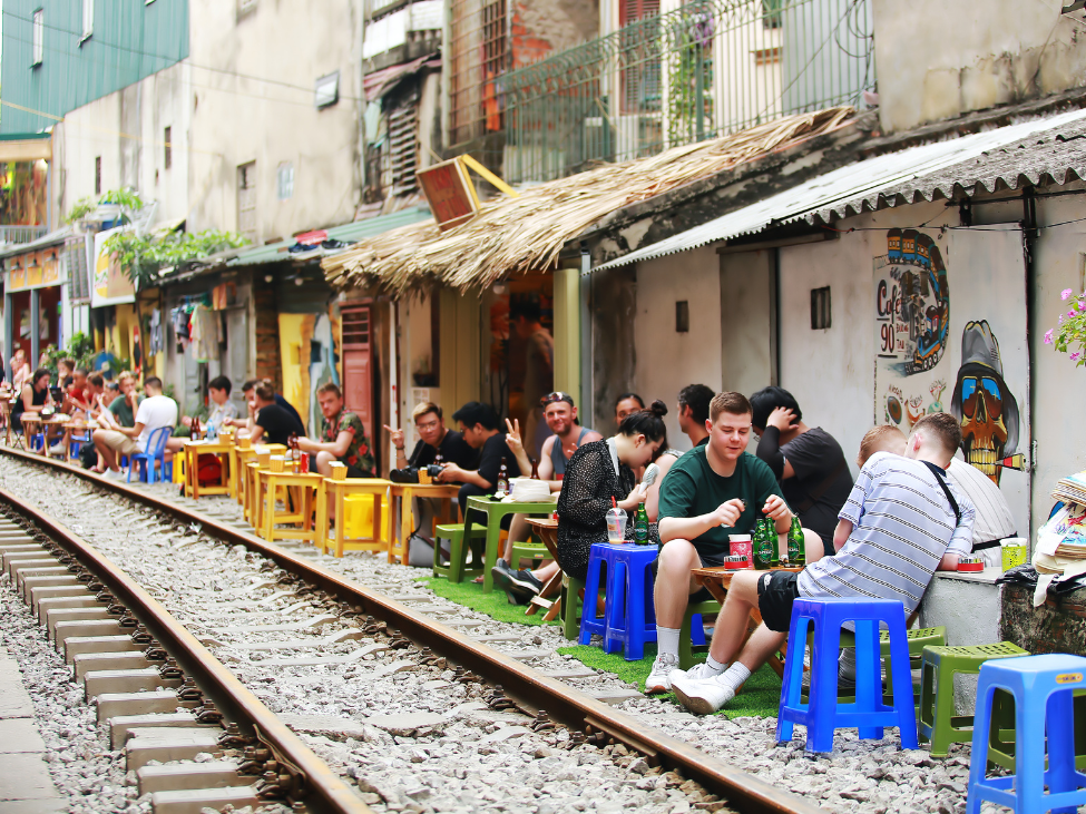 A vibrant view of Hanoi Train Street with visitors enjoying trackside cafes.