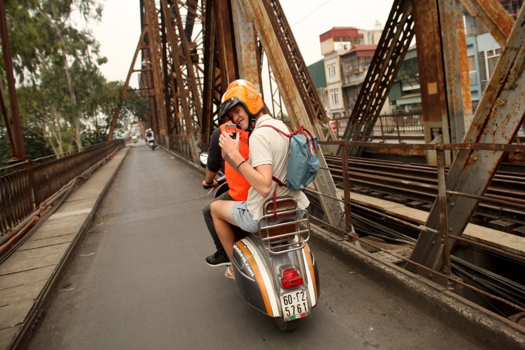 A photographer capturing the intricate details of Long Bien Bridge at sunset.