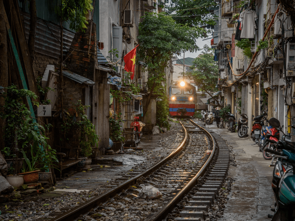 Train passing through a narrow street surrounded by residential buildings in Hanoi.