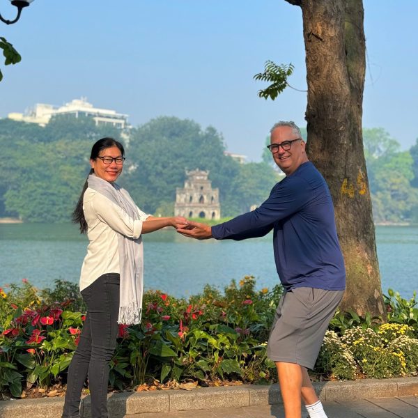 Turtle Tower on Hoan Kiem Lake framed by lush green trees.