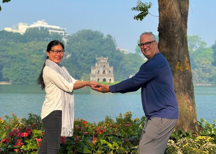 Turtle Tower on Hoan Kiem Lake framed by lush green trees.