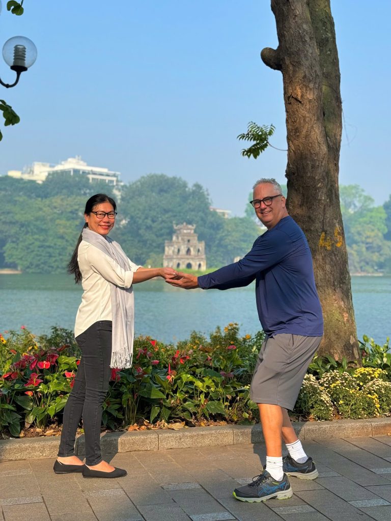 Turtle Tower on Hoan Kiem Lake framed by lush green trees.