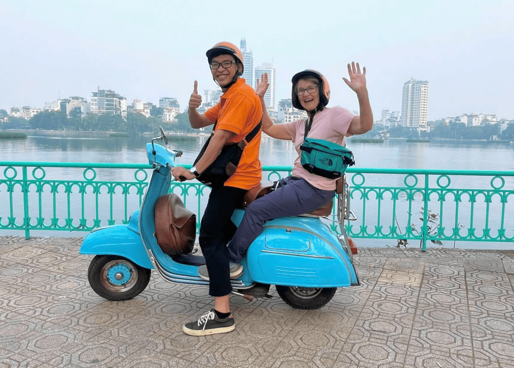 A Vespa rider cruising past Hoan Kiem Lake in Hanoi.