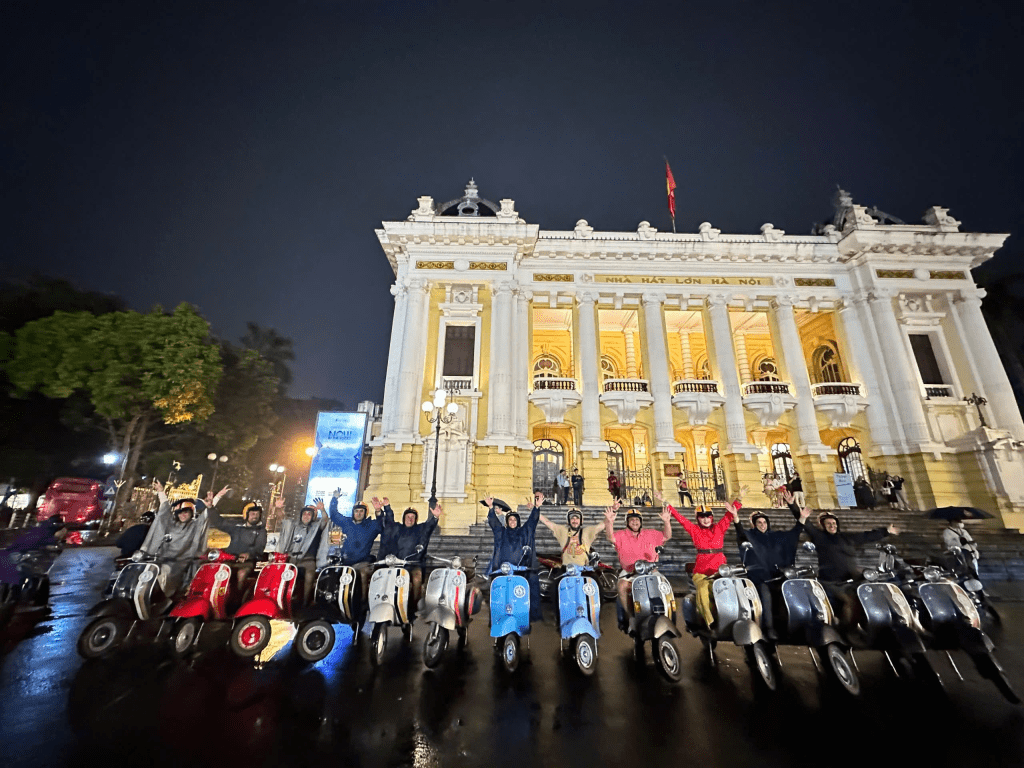 Group of travelers enjoying a street food tour in Hanoi on vintage Vespas.