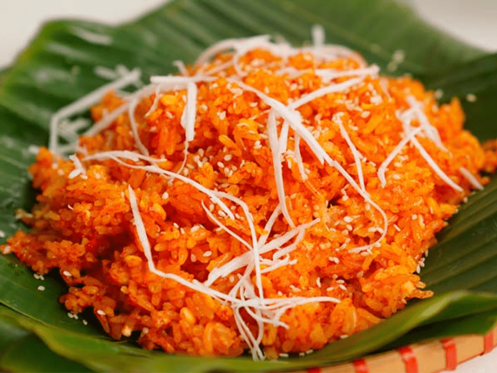 A bowl of red sticky rice (Xoi Gac) with sesame seeds.