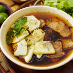 A bowl of Bun Cha with grilled pork, noodles, and herbs.